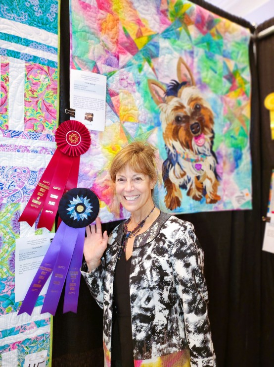 The artist beside the quilt with its Second Place and Viewer's Choice ribbons