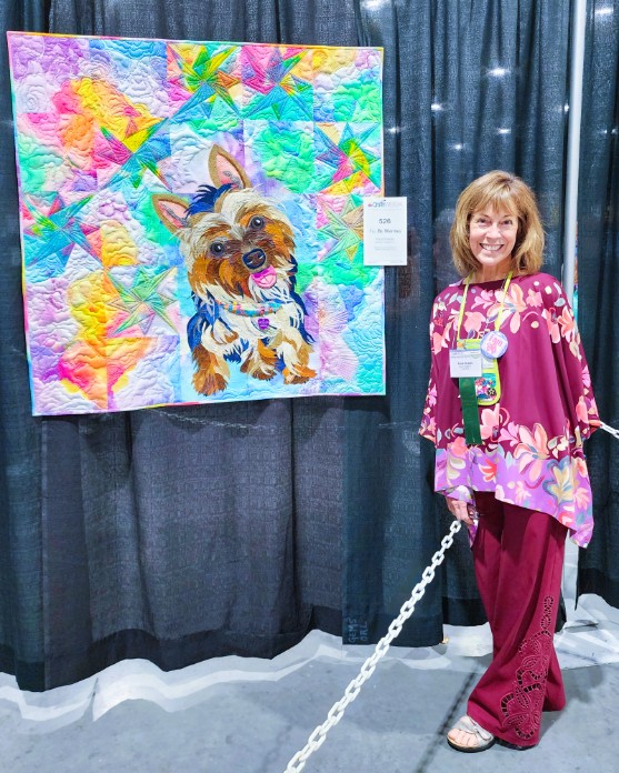 The artist standing next to the quilt at the AQS Daytona Beach Show