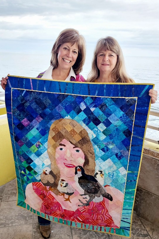 Two women holding the finished Chicken Tender quilt